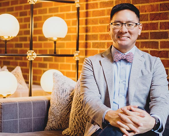 Sam Kim wearing blazer sitting with hands clasped 