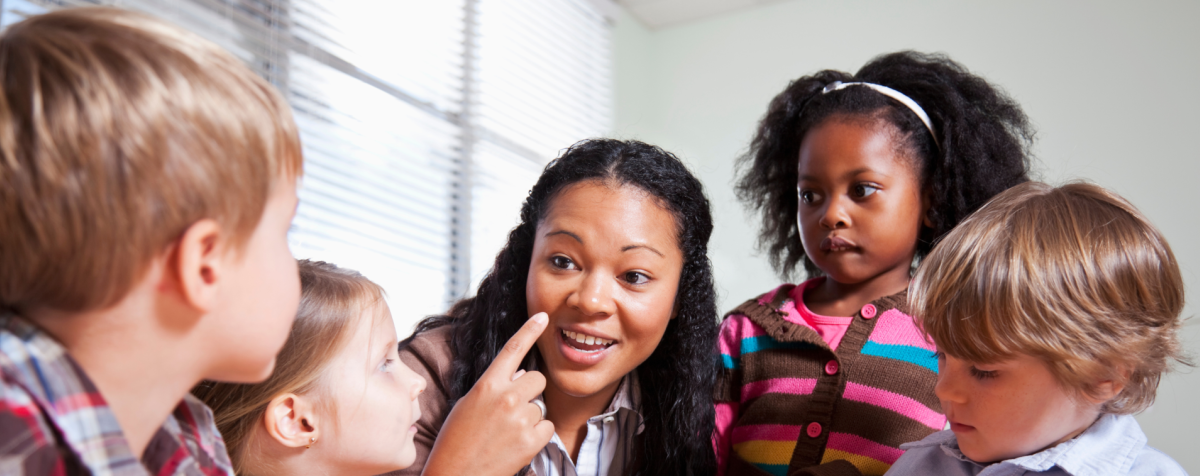 Preschoolers listen to a teacher as she talks.