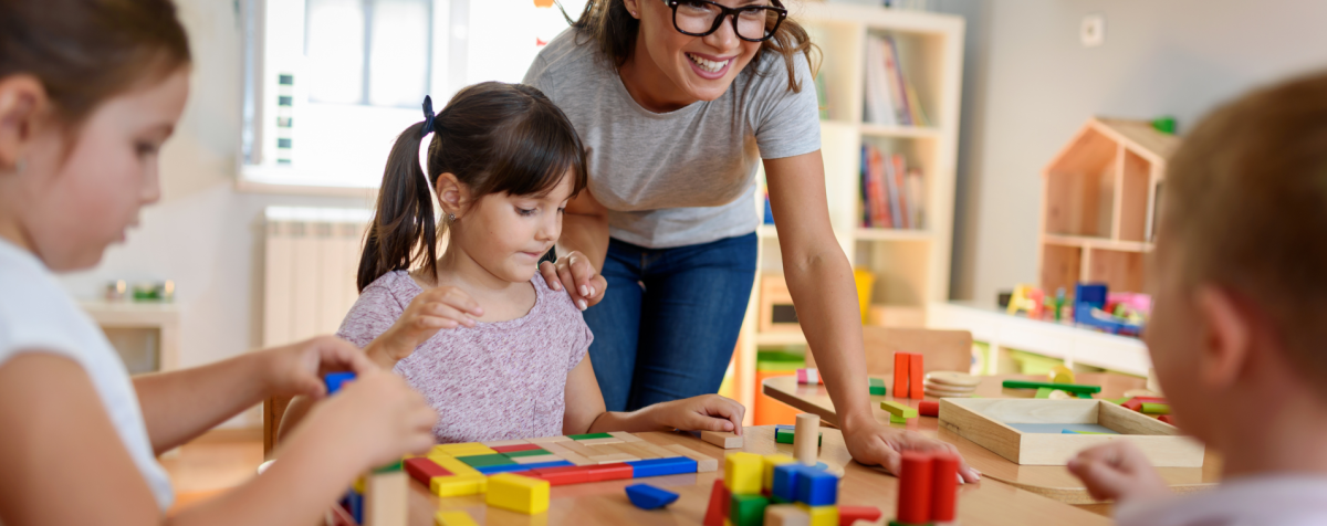 Teacher watches children playing with blocks