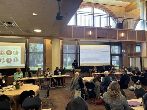 A speaker at DU's School Board Symposium presents information to a full room of participants.